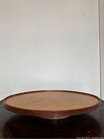 Side view showing the recessed rotating base and visible rim of the Lazy Susan on a dark surface against a plain light background.