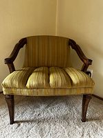 Front view of vintage mid-century chair showing yellow striped upholstery and wooden armrests and legs.