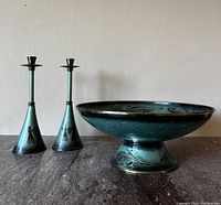 Front view of two brass candlesticks and one pedestal bowl with green verdigris enamel finish and Judaica decorations.