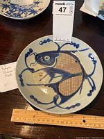 Antique Chinese ceramic plate showing fish design with ruler for size reference.