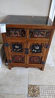 Front view of Asian storage cabinet showing two top drawers and two front doors with decorative painted panels and metal hardware.