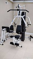 Front view of home gym showing frame, seat, pulldown and press arms