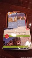Photo of Thomas Guide 2006 Los Angeles & Orange Counties street guide and two Phoenix street maps (Phoenix West and Phoenix East) stacked in a basket