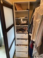 Tall shelving unit with folded mens clothing and drawers partly open.