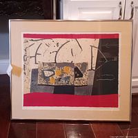 Full view of framed abstract print resting against a piece of furniture, showing the entire artwork and frame.