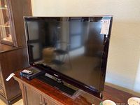 Samsung LN46C550 TV with remote and DVD player on wooden cabinet