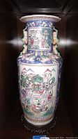 Front view of hand painted ceramic vase with detailed traditional scenes and blue background