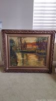 Full view of framed painting showing riverside landscape and frame details