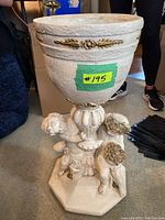 Full view of floor planter showing top bowl with gold decorative bands and base with three cherubs on octagonal platform.