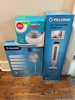 Three boxed household items: Pelonis 40-inch oscillating tower fan, Pelonis 16-inch oscillating pedestal fan, and Life brand vaporizer.