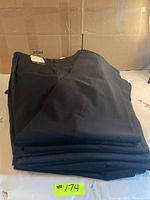 Stack of nine pairs of black men's trousers neatly folded.