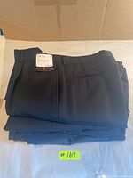 Folded stack of men's trousers with visible tag showing brand and size.