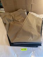 Stack of men's trousers in beige, black and navy colors.