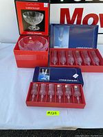 Overview of the boxed sets with 6 large glasses, 6 small glasses, and bowl on table.
