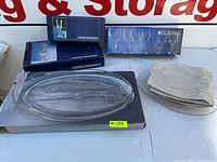 Photo showing boxed Cristal d'Arques Longchamp champagne flutes, Claudia glasses, oval fish platter, and stacked rectangular serving plates.