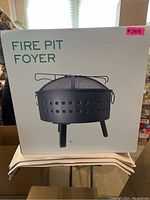 Front view of the sealed white box with image of black Fire Pit Foyer fire pit and pink label #203 on the upper right corner.