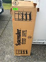 Photo showing the front of the packaging box with the product illustration and branding "Spacemaker" and shelving details.