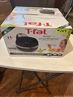 Photo of T-Fal ActiFry Plus air fryer in original box with front view and product branding visible.