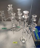 Two crystal candelabras displayed side by side on a table, showing their arms, candle holders and hanging crystals.