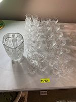 Full set of crystal glassware including vase and 26 glasses arranged on a table.