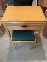 Front view of Singer sewing machine cabinet with stool tucked in and roll-top drawer closed
