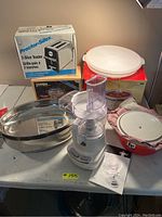 Overview of lot showing boxed Proctor-Silex toaster, Pyrex baking dish, white food processor, and ceramic cookware with lids.
