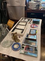 Table with tennis-themed bookends, boxed picture frames, and decorative items arranged, including a large glass jug.