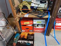 Black and Decker saw, drill, basic jigsaw on shelf with boxes labeled plumbing and electric supplies