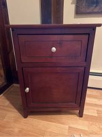 Front view of small wooden cabinet with drawer and door