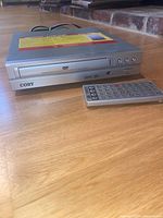 Silver Coby DVD/CD player with front panel controls and remote control placed in front