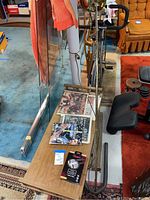 Solid wood rectangular coffee table with spindle legs and railing edge, surface displaying various newspapers.