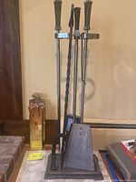 Full view of the fireplace tool set on stand, metal container with matches to the left, heat-resistant slab and pumpkin out of frame