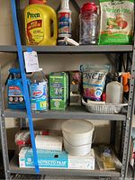 Wide view of metal shelving holding gardening products including Preen weed preventer, plant food, household cleaners, plastic sheets, and miscellaneous containers.