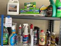 Two metal shelves with various household cleaning items displayed, including bottles of cleaners, Swiffer dry sweep cloth packages, spray bottles, and furniture oil bottles.