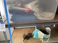 Plastic sheeting stacked on a shelf above two vintage pulleys and a colorful bag