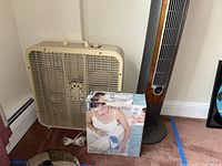 Traditional beige box fan next to ConAir bath spa box on carpet.