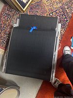 Two brand-new gray woven folding lawn chairs folded flat on floor with visible metal frame.