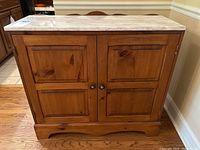 Front view of the wooden sideboard cabinet with marble top, showing two paneled doors with round knobs.