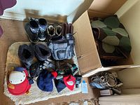 Photo of footwear, hats, gloves, and box of blankets on a small textured rug.