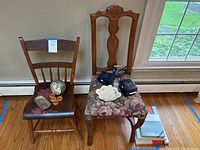 Two vintage wooden chairs with various collectible and kitchen items arranged on the seats and floor next to them