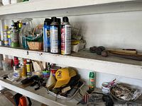Shelves with various cans of auto care sprays, bug sprays, and miscellaneous items such as brushes and a yellow cap.