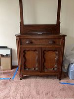 Full view of the vintage solid wood wash stand showing front with drawer and cabinet doors and attached mirror.