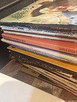 A stack of approximately 50 vinyl records showing album spine titles such as The Beatles and The Concert for Bangla Desh, various classic rock albums.