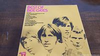 Front cover of yellow "Best of Bee Gees" vinyl album featuring close-up photo of band members and tracklist