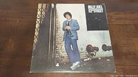 Front cover of Billy Joel 52nd Street vinyl record album showing Billy Joel with saxophone in blue suit against street background.