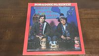 Front cover of the Bob & Doug McKenzie album titled 'Great White North' depicting the two characters sitting with beer mugs, a hockey skate, and snowshoes in the background.