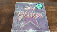 Front cover of Gary Glitter's vinyl album "Glitter" showing star design and artist name in glittery finish