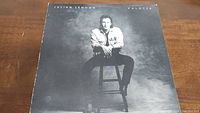 Front cover of Julian Lennon Valotte album showing black and white image of Julian Lennon seated on a stool.
