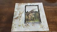 Front cover of the Led Zeppelin IV vinyl album showing the man carrying sticks artwork on a peeling wallpaper background.