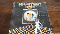 Front cover of Sesame Street Fever vinyl record album showing title, characters, and disco floor.